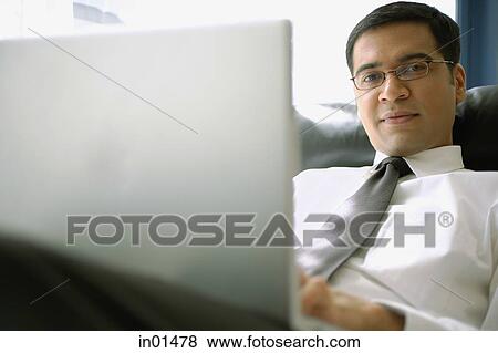 Stock Photo - Businessman with laptop, looking at camera, portrait. Fotosearch