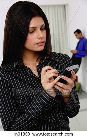 Businesswoman using PDA, people in the background View Large Photo Image Stock Image - Businesswoman using PDA, people in the background. Fotosearch