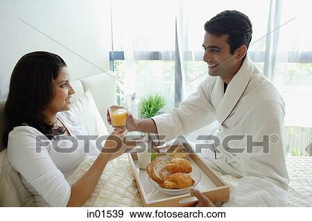 Stock Photo - Couple in bedroom, having breakfast in bed. Fotosearch