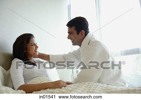Stock Image - Couple in bedroom, looking at each other. Fotosearch