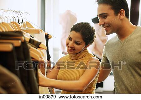 Stock Photo - Couple in clothing store, looking through clothes rack. Fotosearch