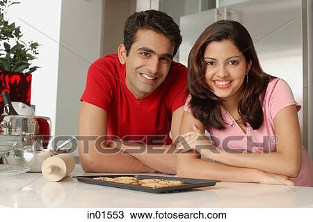 Couple leaning on kitchen counter, looking at camera View Large Photo Image Stock Image - Couple leaning on kitchen counter, looking at camera. Fotosearch