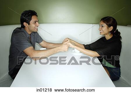 Couple sitting opposite each other, holding hands View Large Photo Image Stock Photo - Couple sitting opposite each other, holding hands. Fotosearch