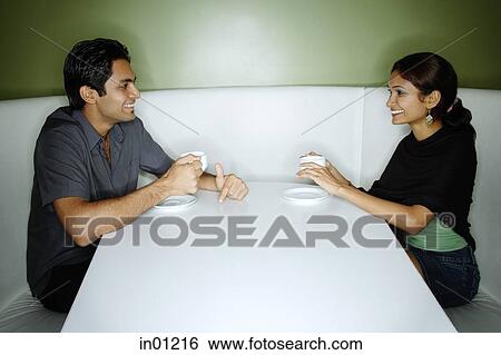 Couple sitting opposite from each other, having tea View Large Photo Image Stock Photograph - Couple sitting opposite from each other, having tea. Fotosearch