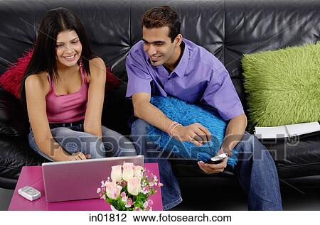 Couple sitting side by side, looking at laptop View Large Photo Image Stock Image - Couple sitting side by side, looking at laptop. Fotosearch