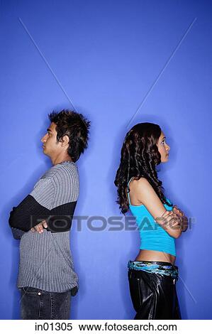 Stock Photography - Couple standing apart against blue wall. Fotosearch