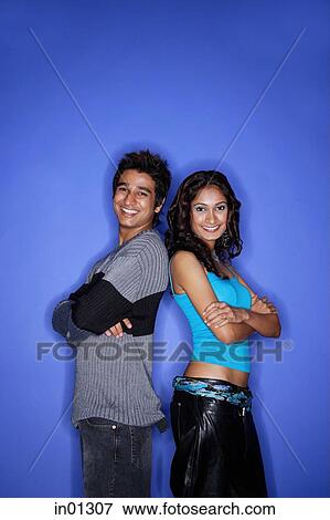 Stock Photo - Couple standing back to back looking at camera. Fotosearch
