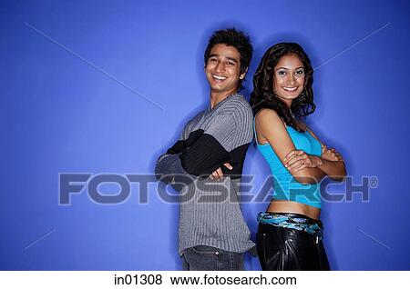 Couple standing back to back smiling at camera View Large Photo Image Stock Photo - Couple standing back to back smiling at camera. Fotosearch