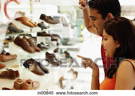 Stock Photography - Couple standing outside shoe shop looking at window display. Fotosearch