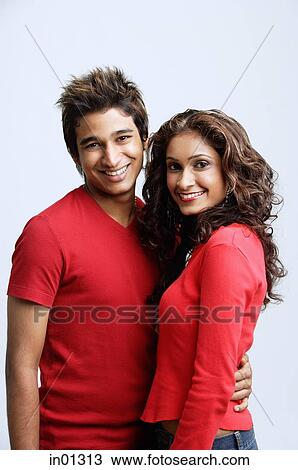 Stock Image - Couple standing side by side, smiling at camera. Fotosearch