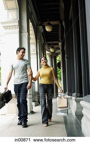 Couple walking, holding hands and carrying shopping bags View Large Photo Image Stock Image - Couple walking, holding hands and carrying shopping bags. Fotosearch