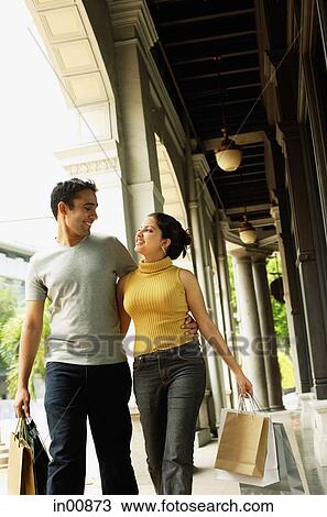 Stock Image - Couple walking, side by side, looking at each other. Fotosearch