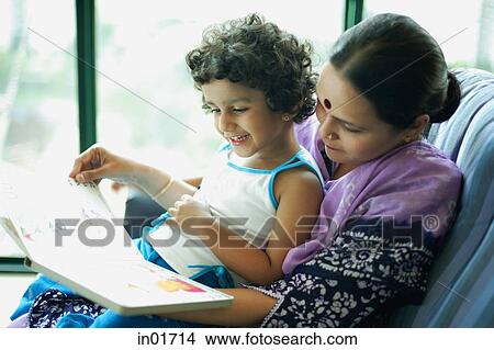 Daughter sitting on mothers lap, reading a book View Large Photo Image Picture - Daughter sitting on mothers lap, reading a book. Fotosearch