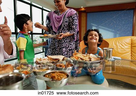 Family of four having a meal at home, mother feeding son View Large Photo Image Stock Photography - Family of four having a meal at home, mother feeding son. Fotosearch