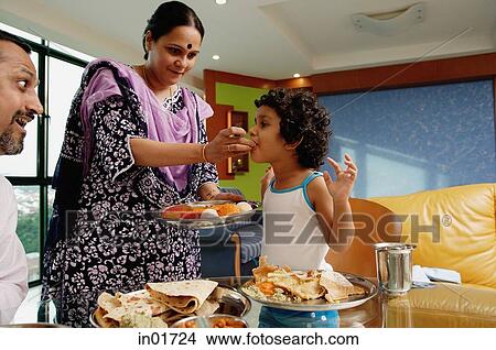 Family of three having a meal at home, mother feeding daughter View Large Photo Image Picture - Family of three having a meal at home, mother feeding daughter. Fotosearch