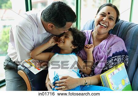 Stock Photograph - Family with one child, father kissing daughter's head, mother smiling at camera. Fotosearch