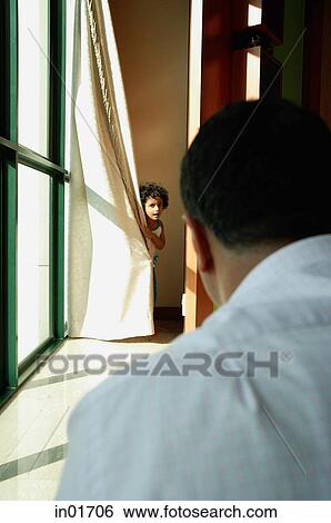 Girl hiding behind curtain, father in foreground looking at her View Large Photo Image Stock Photograph - Girl hiding behind curtain, father in foreground looking at her. Fotosearch