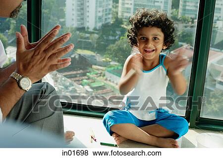 Girl sitting on floor, clapping hands, smiling at camera, father next to her View Large Photo Image Stock Photo - Girl sitting on floor, clapping hands, smiling at camera, father next to her. Fotosearch
