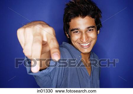 Stock Image - Man against blue background, making hand sign. Fotosearch