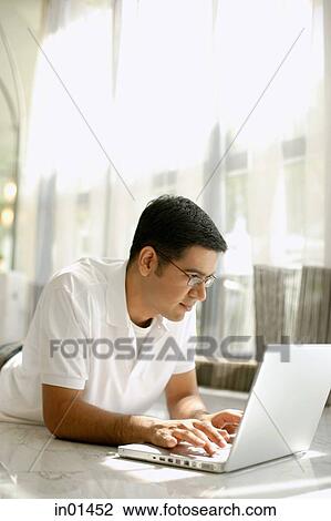 Man at home, lying on floor, using laptop View Large Photo Image Stock Image - Man at home, lying on floor, using laptop. Fotosearch