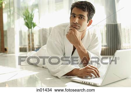 Picture - Man in bathrobe, hand on chin, looking at camera. Fotosearch