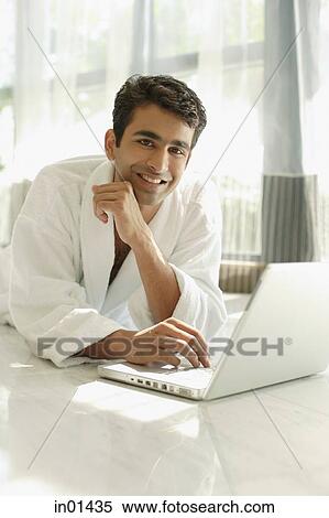 Man in bathrobe, using laptop, hand on chin, smiling at camera View Large Photo Image Stock Photography - Man in bathrobe, using laptop, hand on chin, smiling at camera. Fotosearch