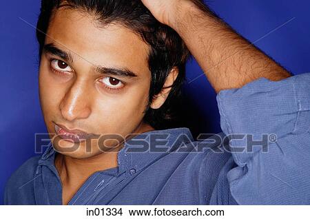 Man in blue shirt against blue background, hand on head View Large Photo Image Picture - Man in blue shirt against blue background, hand on head. Fotosearch