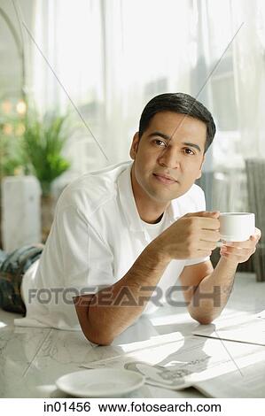 Man lying on floor holding cup, looking at camera View Large Photo Image Stock Photograph - Man lying on floor holding cup, looking at camera. Fotosearch
