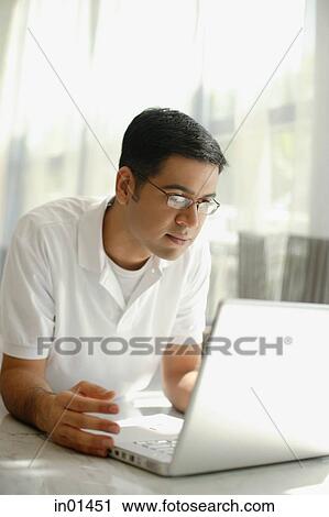 Stock Image - Man lying on floor, using laptop. Fotosearch