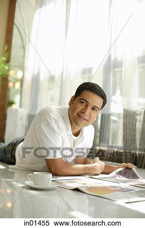 Man lying on floor with newspaper, looking at camera View Large Photo Image Stock Photography - Man lying on floor with newspaper, looking at camera. Fotosearch
