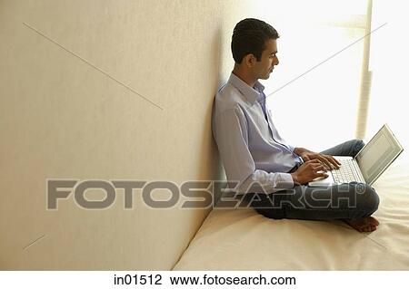 Man sitting cross-legged on bed, using laptop View Large Photo Image Stock Image - Man sitting cross-legged on bed, using laptop. Fotosearch