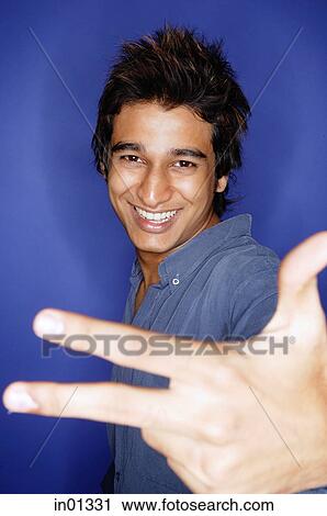 Stock Image - Man smiling, making hand sign. Fotosearch