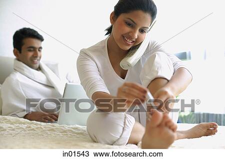 Man using laptop, woman using telephone and painting her nails View Large Photo Image Stock Image - Man using laptop, woman using telephone and painting her nails. Fotosearch