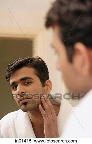 Man wearing bathrobe, looking in mirror, touching his face View Large Photo Image Stock Photography - Man wearing bathrobe, looking in mirror, touching his face. Fotosearch