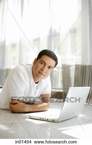 Picture - Man with laptop, looking at camera. Fotosearch
