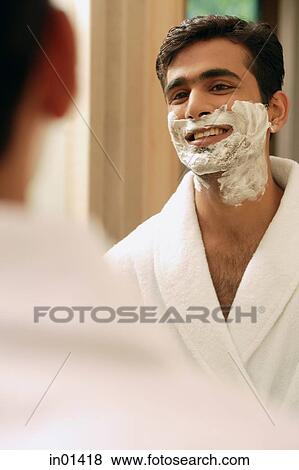 Stock Photo - Man with shaving cream on face, looking in mirror. Fotosearch