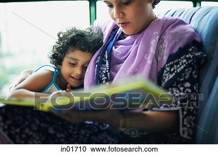 Stock Image - Mother and daughter sitting down at home going through photo album. Fotosearch