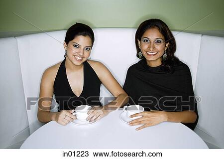 Stock Image - Two women having tea, looking at camera. Fotosearch