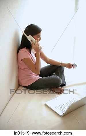 Woman at home, holding credit card, using cordless phone View Large Photo Image Stock Photo - Woman at home, holding credit card, using cordless phone. Fotosearch