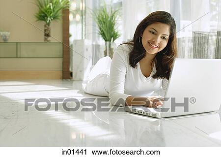 Stock Image - Woman at home using laptop, smiling. Fotosearch