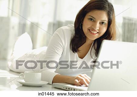 Stock Photography - Woman at home with laptop, smiling at camera. Fotosearch