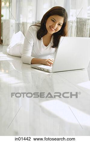 Woman dressed in white, lying on white floor, using laptop View Large Photo Image Stock Image - Woman dressed in white, lying on white floor, using laptop. Fotosearch