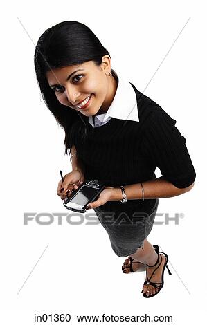 Stock Image - Woman holding PDA, smiling at camera. Fotosearch