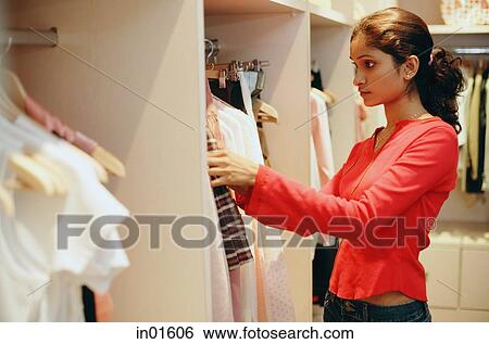 Woman in clothing store, looking through clothes on rack View Large Photo Image Stock Photograph - Woman in clothing store, looking through clothes on rack. Fotosearch
