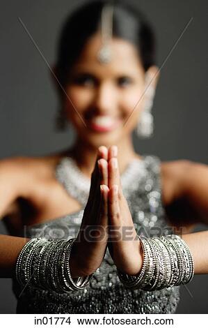 Picture - Woman in gray sari smiling at camera, hands together, selective focus. Fotosearch
