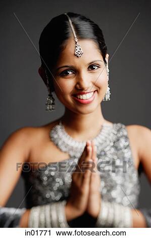 Stock Image - Woman in gray sari smiling at camera, hands together. Fotosearch