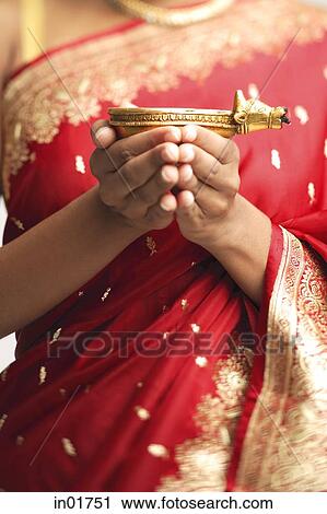 Stock Image - Woman in sari holding oil lamp, cropped image. Fotosearch