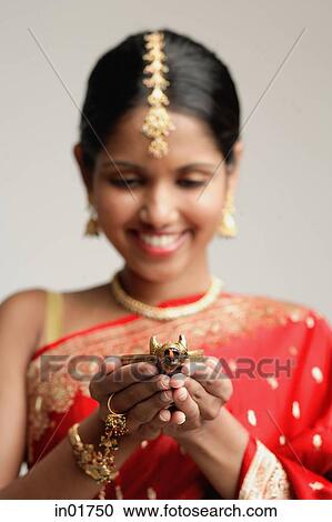 Stock Image - Woman in sari, holding oil lamp. Fotosearch