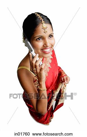 Stock Image - Woman in sari, using mobile phone, smiling. Fotosearch