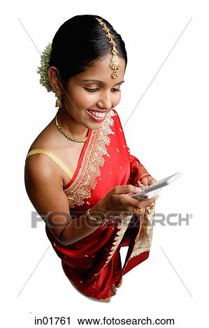 Stock Image - Woman in sari, using mobile phone, text messaging. Fotosearch